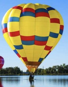 Yellow hot air balloon with red and blue checkers arranged in oval patterns
